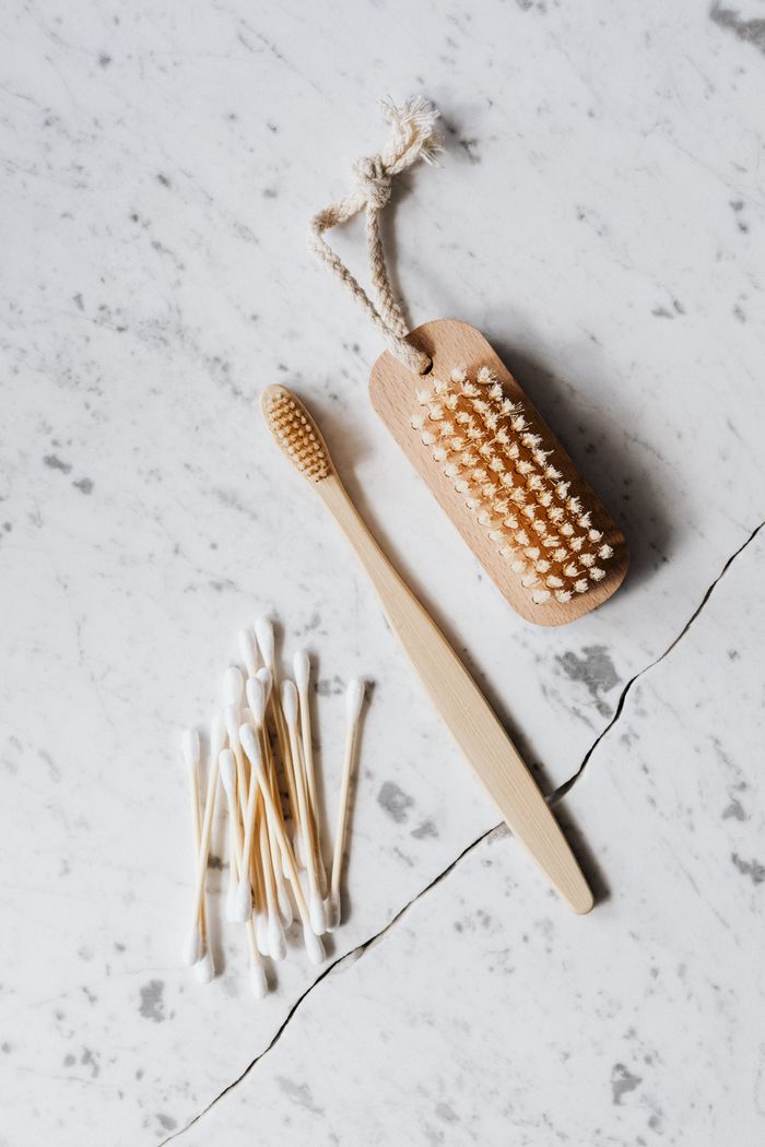 hero-01 Top view layout of wooden cleaning brush and cotton swab placed on marble surface near wooden toothbrush on line chop